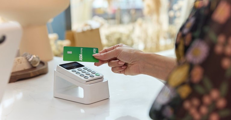 A woman pays at a contactless machine using an Asda Money Credit Card