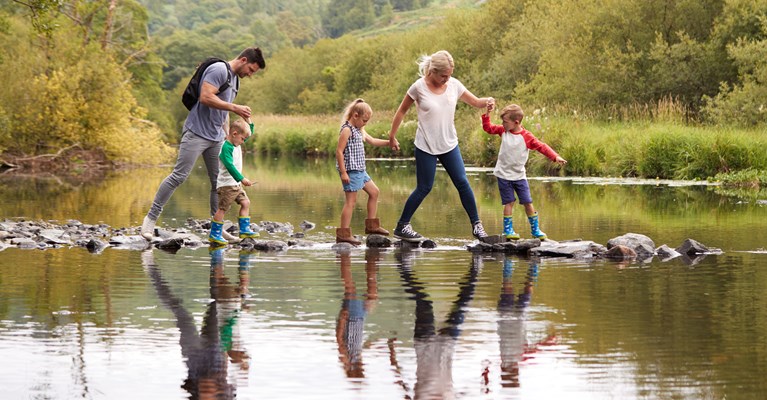 Family walking along rocks in along a lake