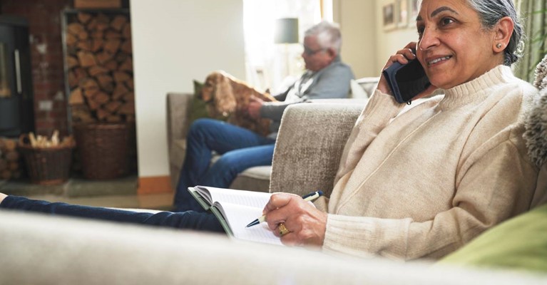 A woman on the phone while writing in a notepad