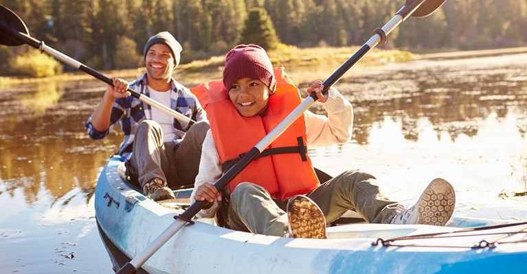 Dad and son in kayak on lake smiling and having fun