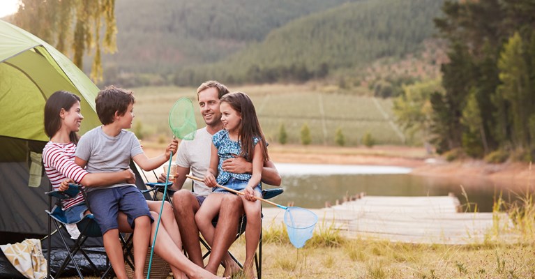 Young family camping by lake with fishing nets