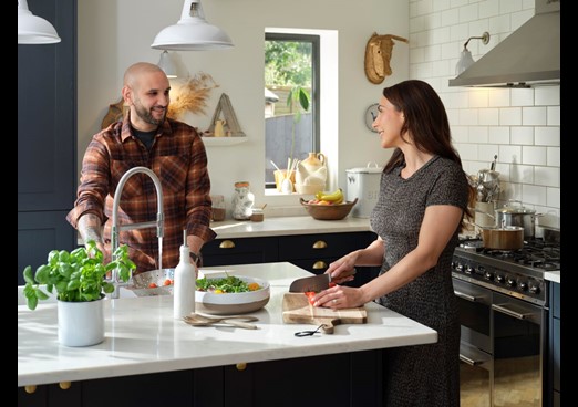 A young couple stand at a kitchen counter and talk