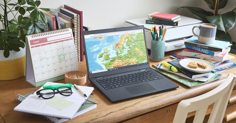 A laptop on a table with a world map displayed on the screen