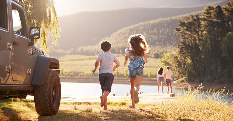 Young children running towards parents and lake