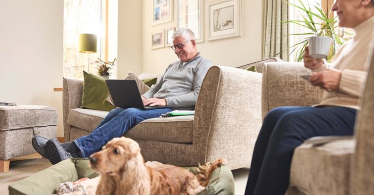 An elderly couple sat in the living room with their dog