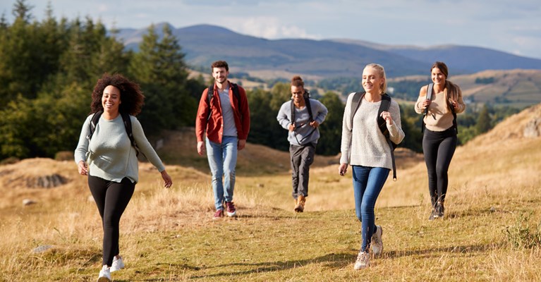 Young group of friends walking through the hills in nature