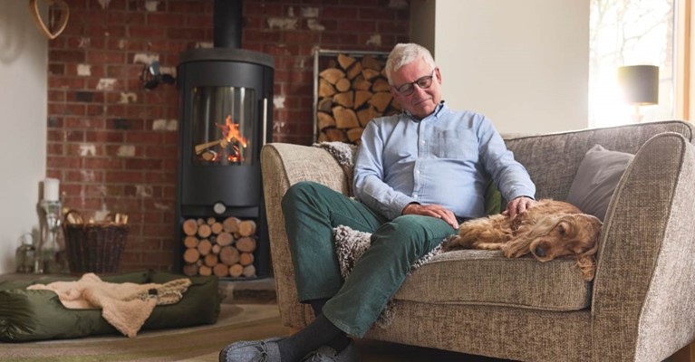 A man sits on a sofa next to a dog