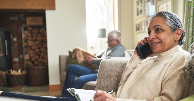 A woman writes on a notepad whilst on the telephone